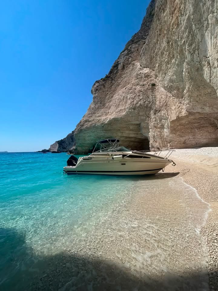The MareWaves boat pulled up on the pebbles of a small empty cove under a white cliff, clear turquoise shallows in front