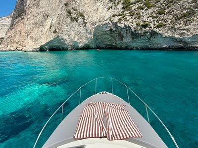 The bow sunbeds of the boat facing turquoise water and dark cave openings at the foot of the west coast cliffs