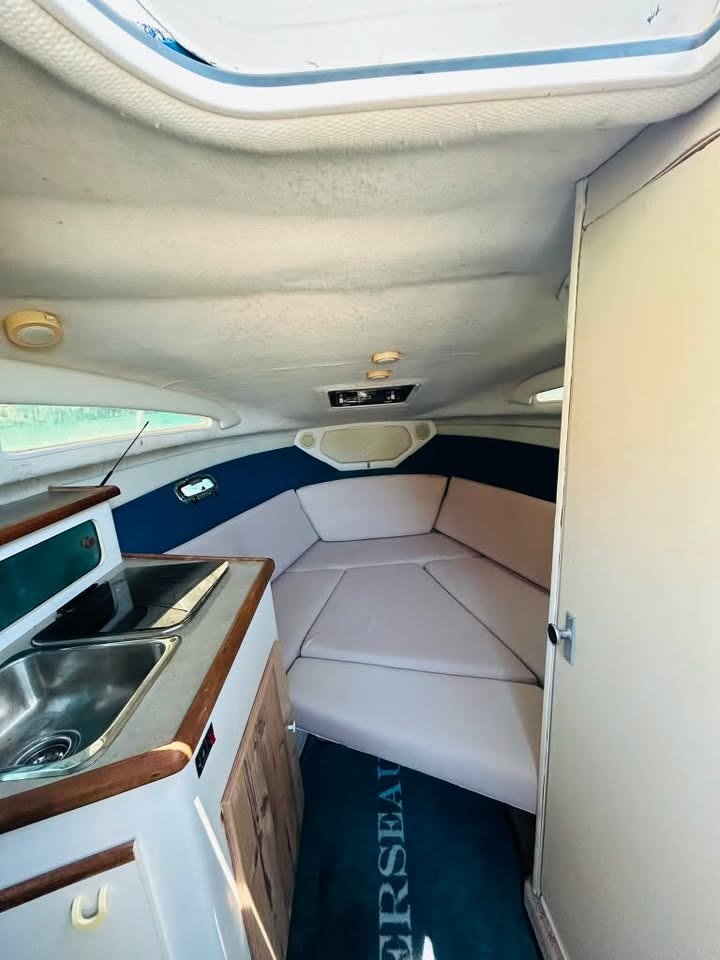 The cabin below deck on the MareWaves boat, with a cushioned V-berth, galley sink and navy trim